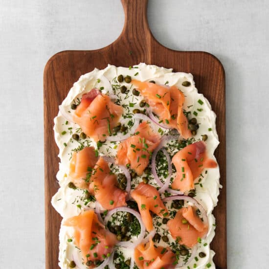 smoked salmon pizza on a wooden cutting board.