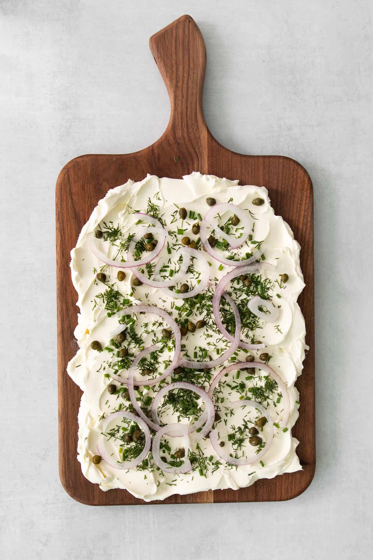 a pizza with onions and cheese on a wooden cutting board.