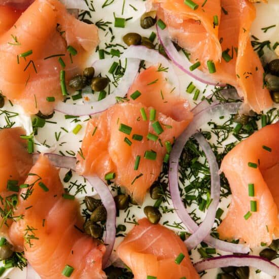 a pizza with smoked salmon, onions and capers.
