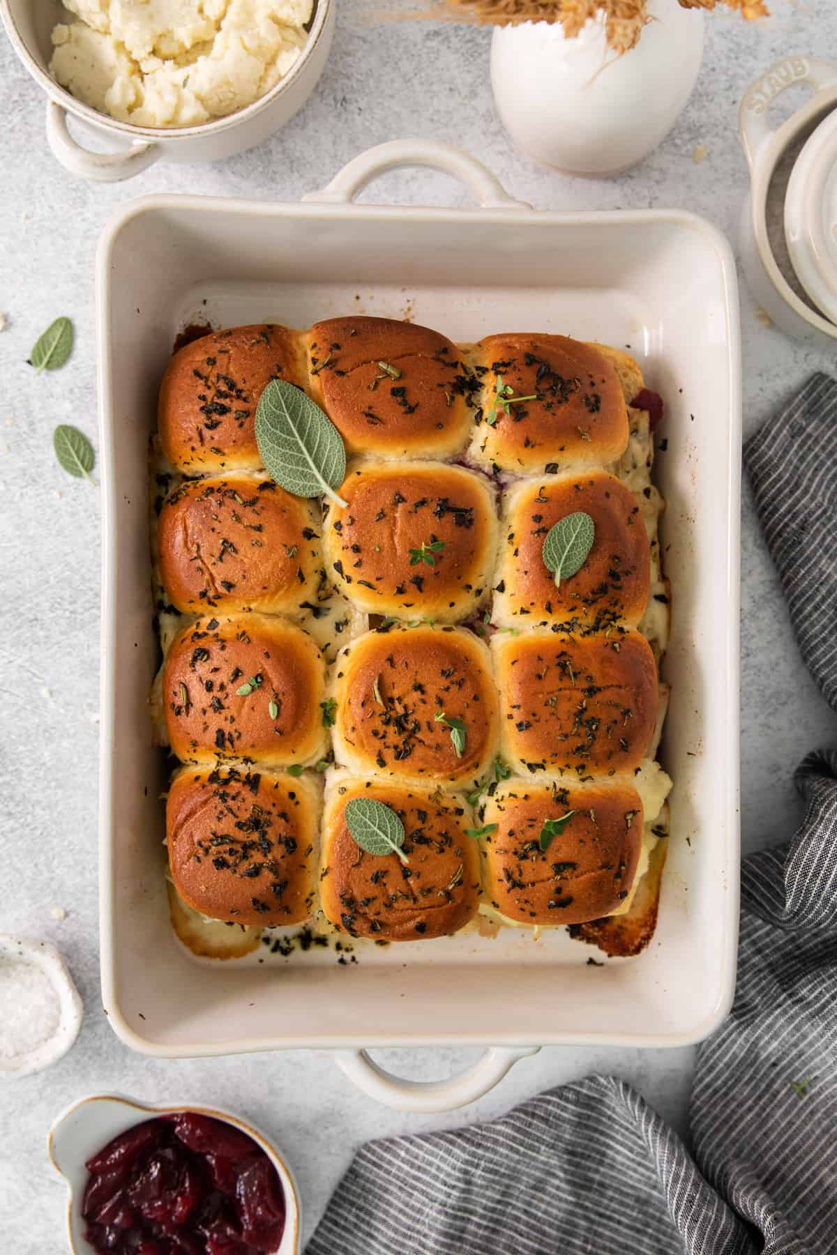 Turkey sliders in a white dish with cranberry sauce.