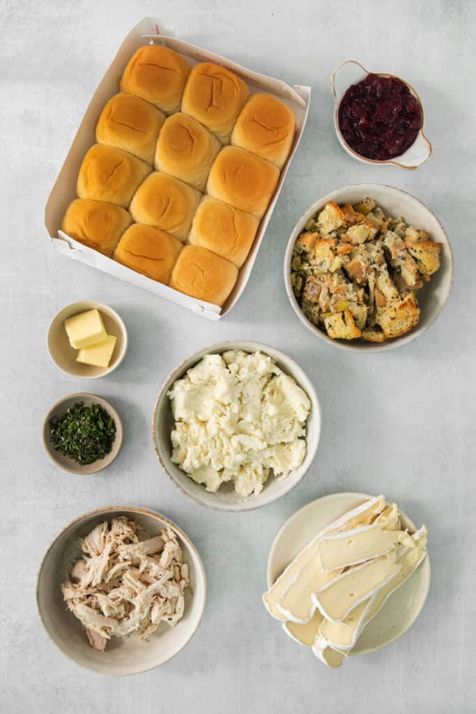A variety of breads, rolls, mashed potatoes and cranberry sauce on a table.