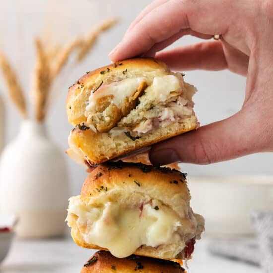A person holding up a stack of stuffed chicken sliders.