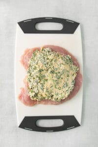Chicken breast with spinach on a cutting board.