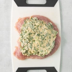 Chicken breast with spinach on a cutting board.