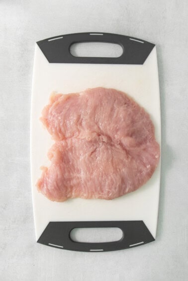 A piece of chicken on a cutting board.