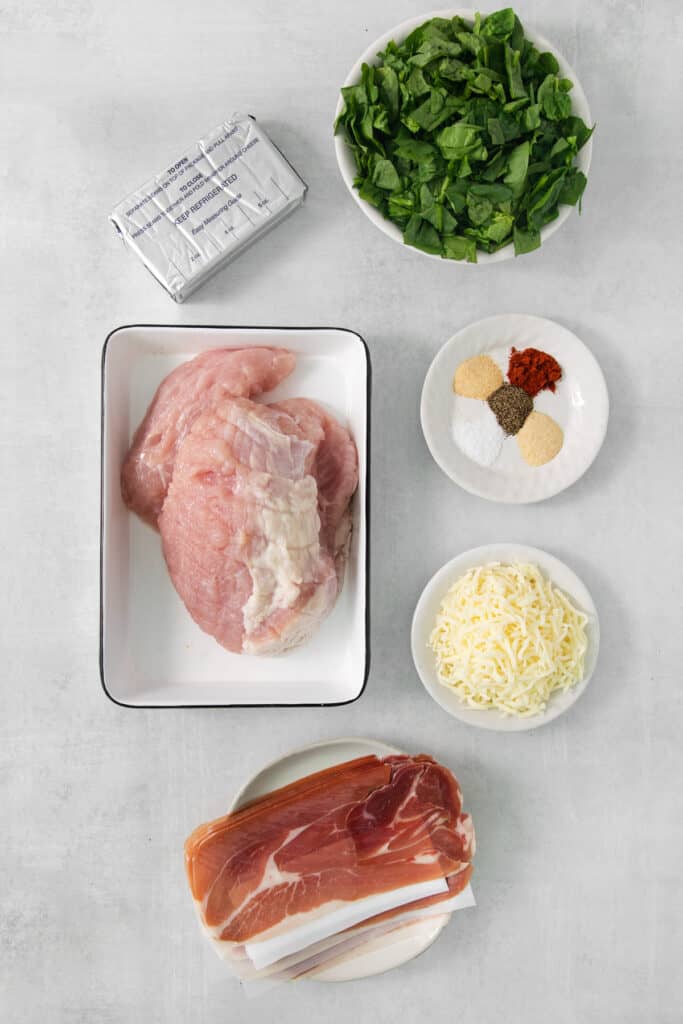 The ingredients for a chicken parmigiana are laid out on a table.