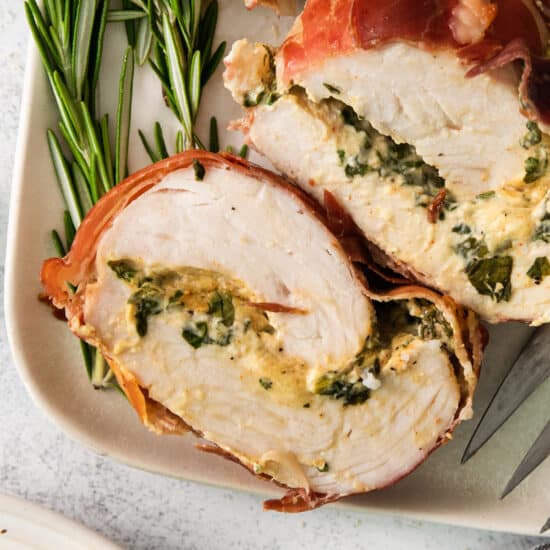 Turkey stuffed with spinach and herbs on a white plate.