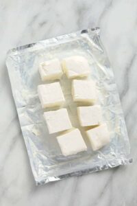 A plastic bag containing tofu on a marble countertop.