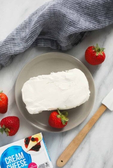 A plate with cream cheese and strawberries, alongside a guide on how to soften the cream cheese.