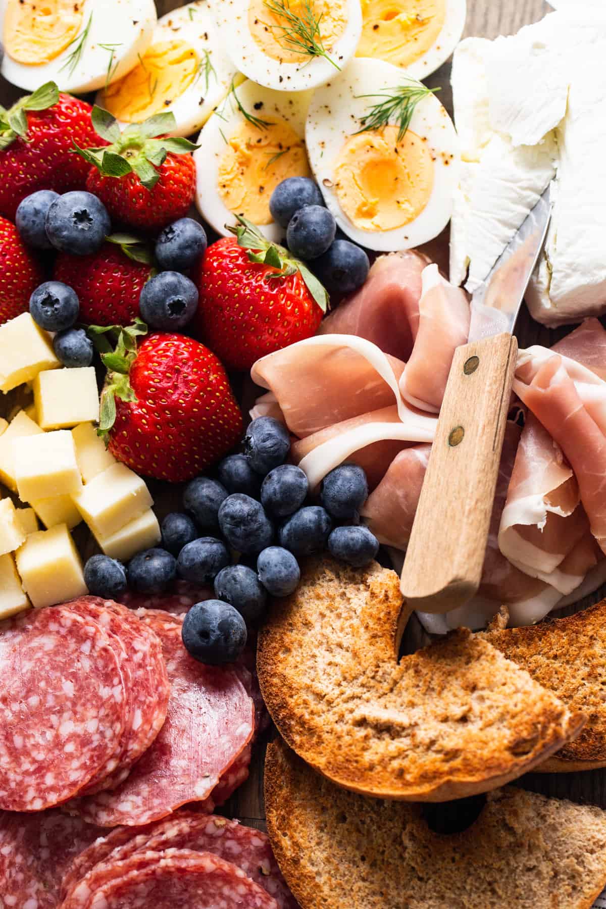 A plate with a variety of meats, cheeses, and fruit.