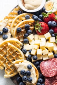 A platter of waffles, cheese, and fruit.