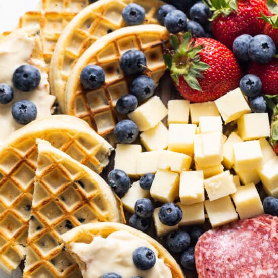 A platter of waffles, cheese, and fruit.