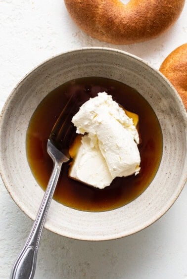 A bowl of bagels with cream and a fork.