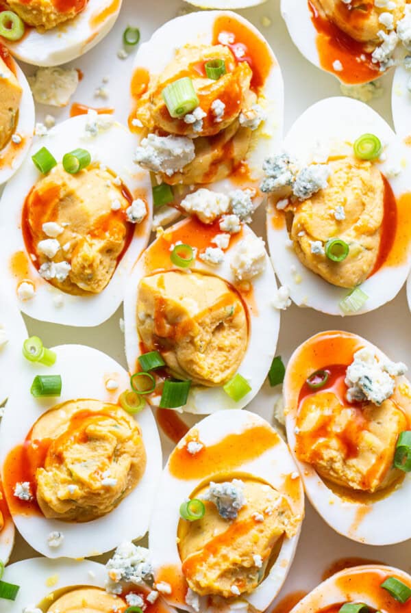 Deviled eggs topped with sauce and green onions.