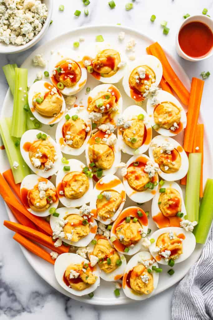 Deviled eggs on a plate with celery and carrots.