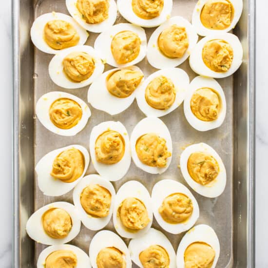 Deviled eggs on a baking sheet with mustard.