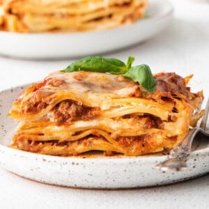 Lasagna on a white plate with a fork.