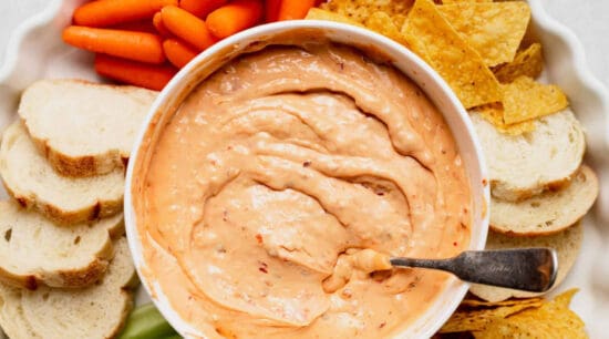 A bowl of dip with carrots and celery.