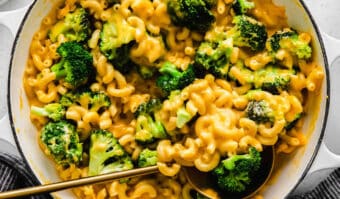 Macaroni and broccoli in a pan with a gold spoon.