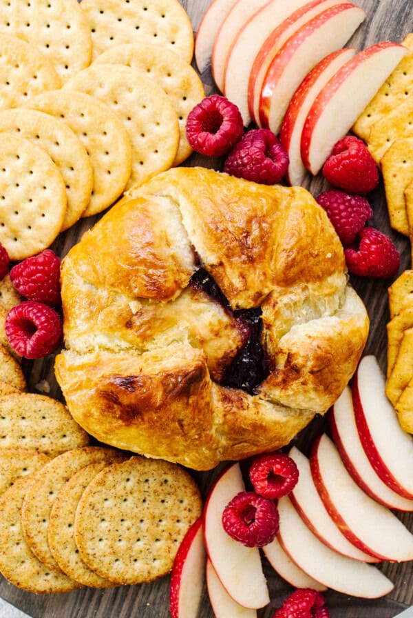 A platter of fruit, crackers and crackers.