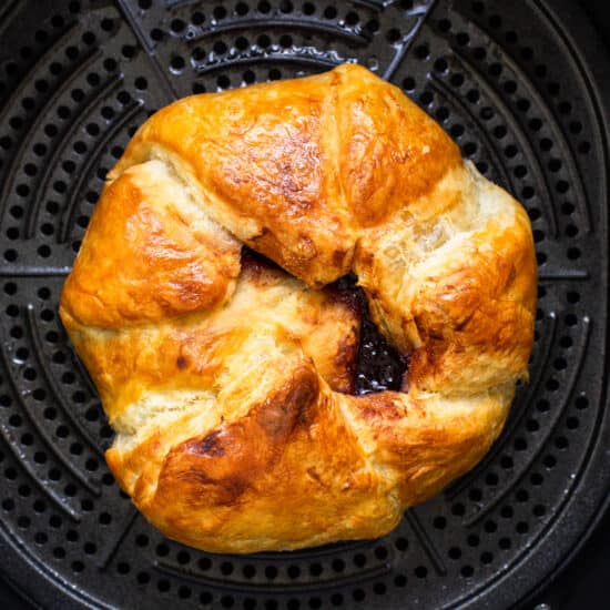 A croissant is sitting in an air fryer.