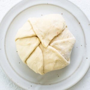 A white plate with a piece of dough on it.