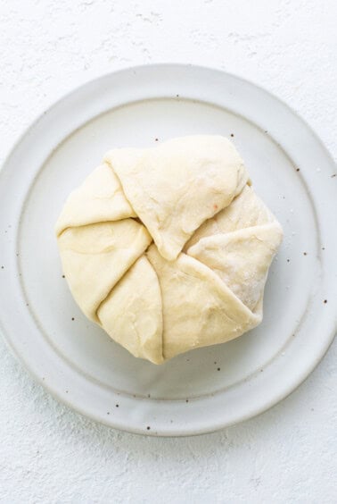 A white plate with a piece of dough on it.