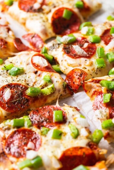 A slice of pepperoni pizza with green peppers and onions.