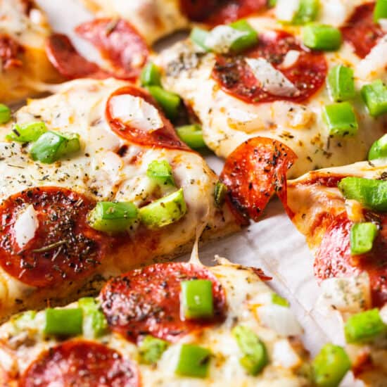 A slice of pepperoni pizza with green peppers and onions.