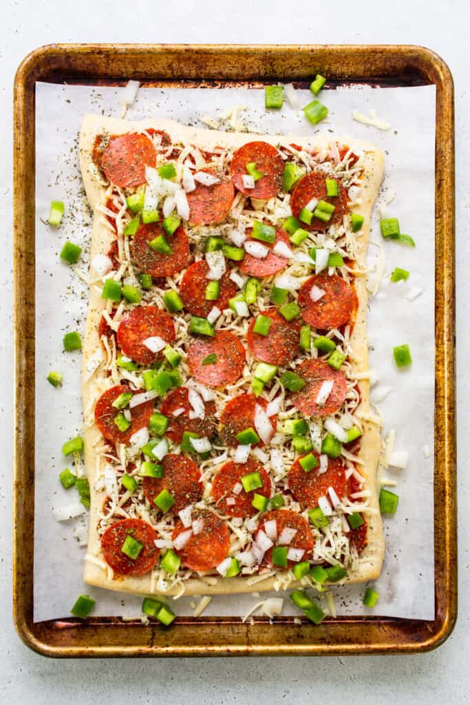 Pepperoni pizza on a baking sheet with green onions.