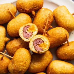 A plate full of fried meatballs with toothpicks.