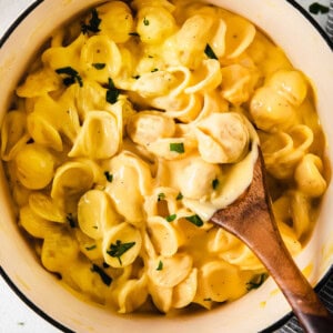 Macaroni and cheese in a pot with a wooden spoon.