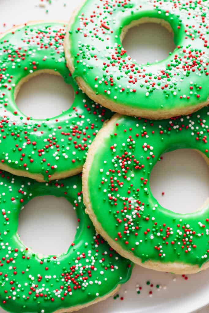A plate of cookies with green frosting and sprinkles.