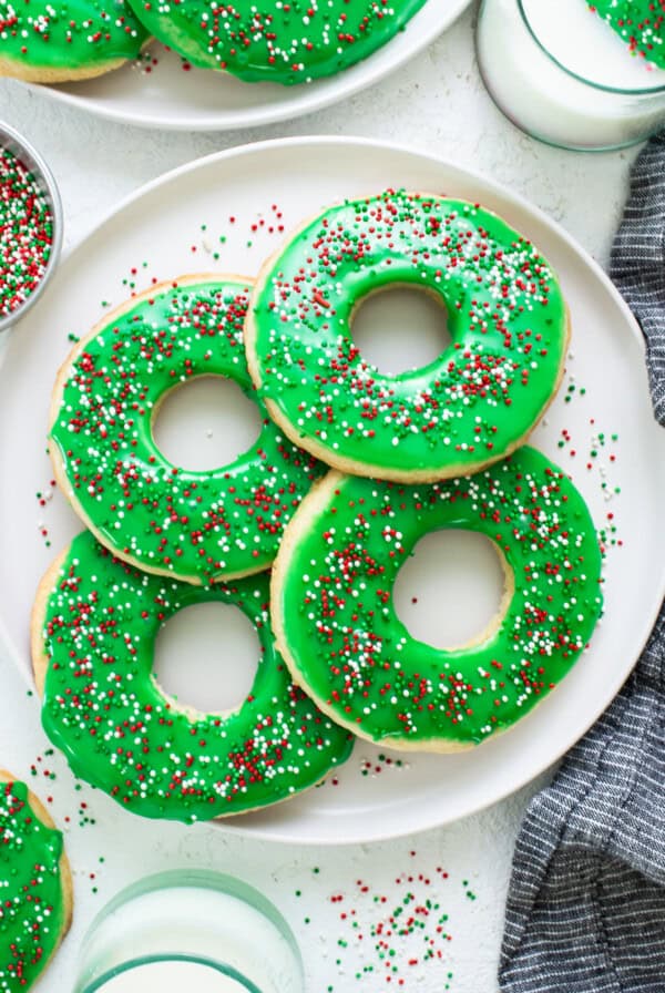 Donuts with green icing and sprinkles on a plate.