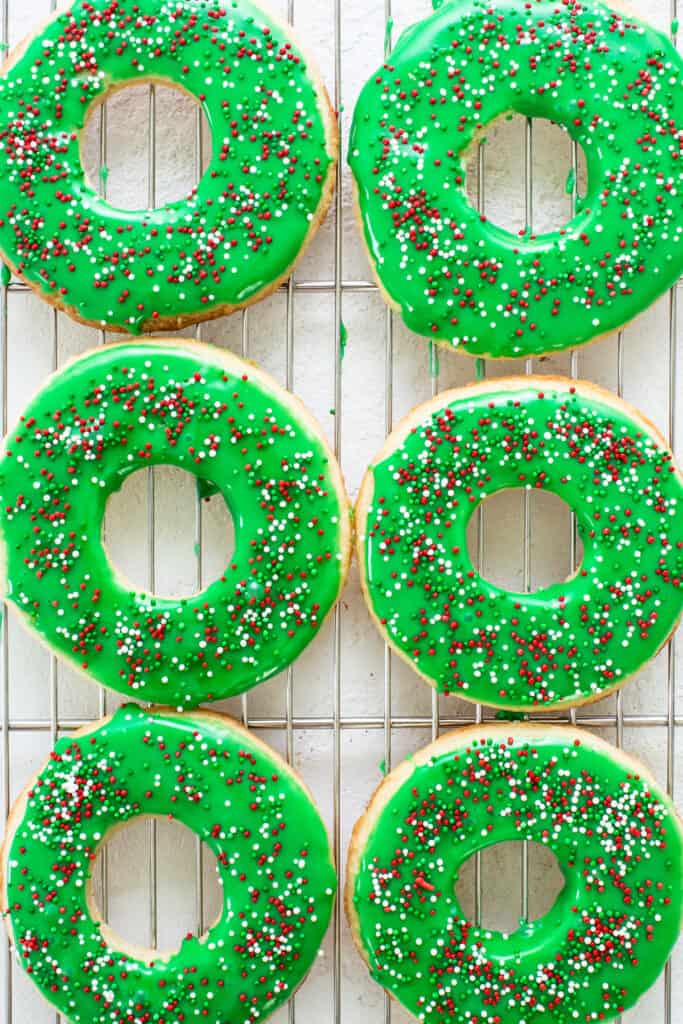Four green frosted doughnuts on a cooling rack.