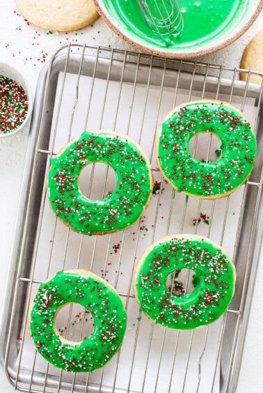 Donuts on a cooling rack with green icing and sprinkles.
