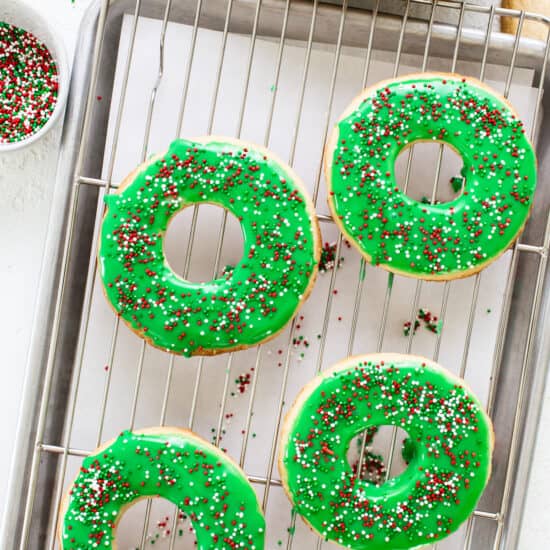 Donuts on a cooling rack with green icing and sprinkles.