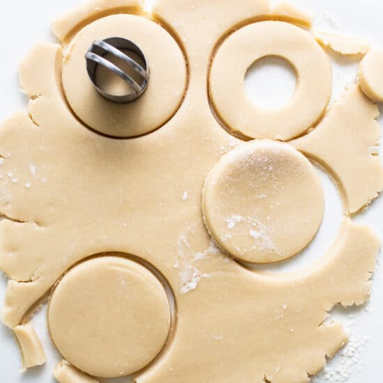 A sheet of cookie dough with a cookie cutter on it.