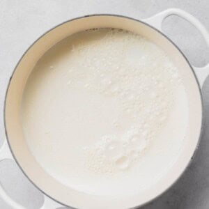 Ricotta melting in a pan on a white surface.