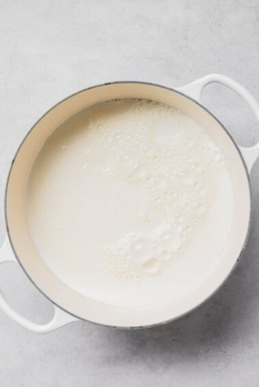 Ricotta melting in a pan on a white surface.