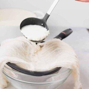 A person pouring ricotta into a glass bowl.