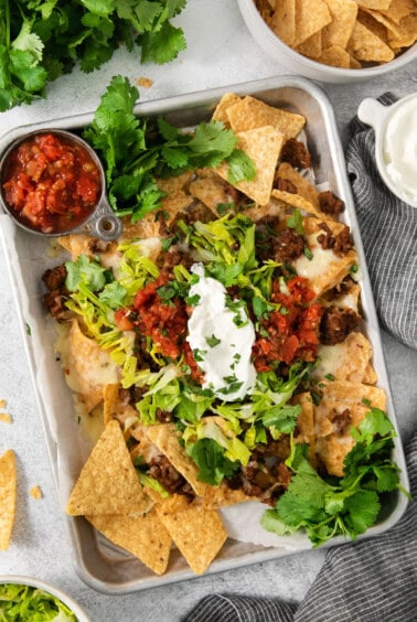 Mexican nachos on a tray with sour cream and guacamole.