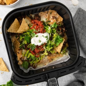 An air fryer filled with nachos and sour cream.