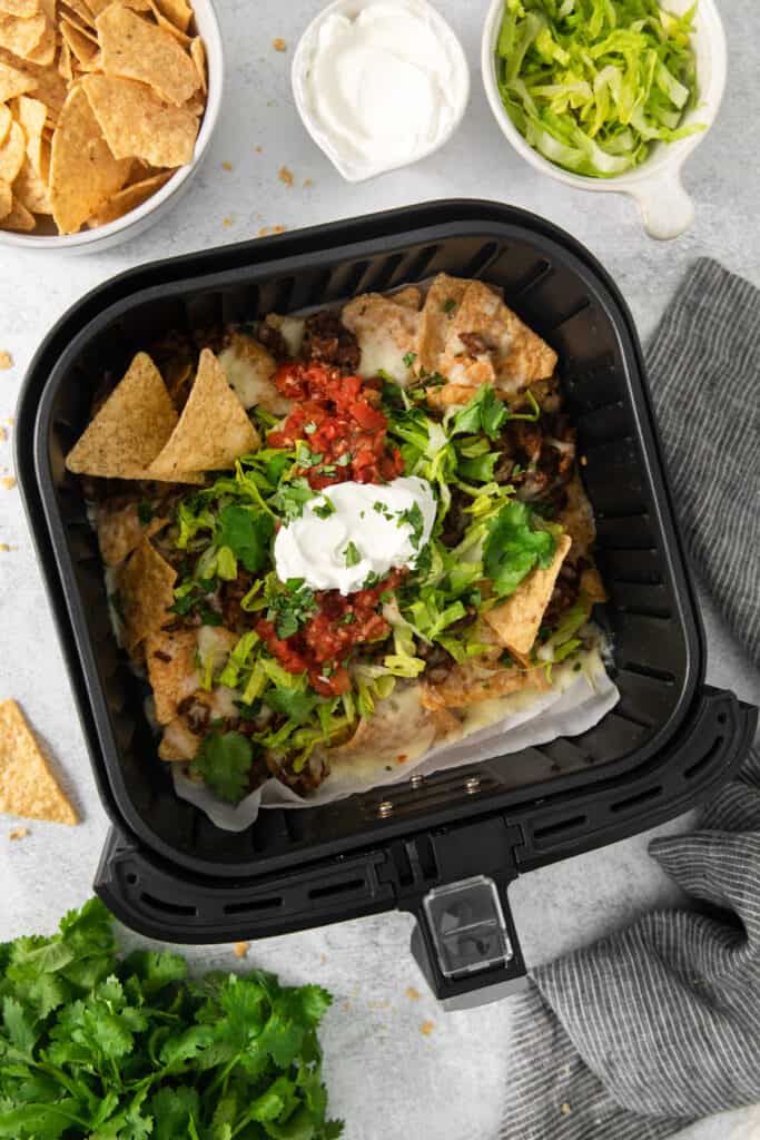 An air fryer filled with nachos and sour cream.