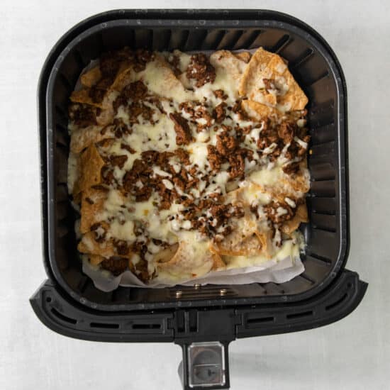 An air fryer filled with cheesy nachos.