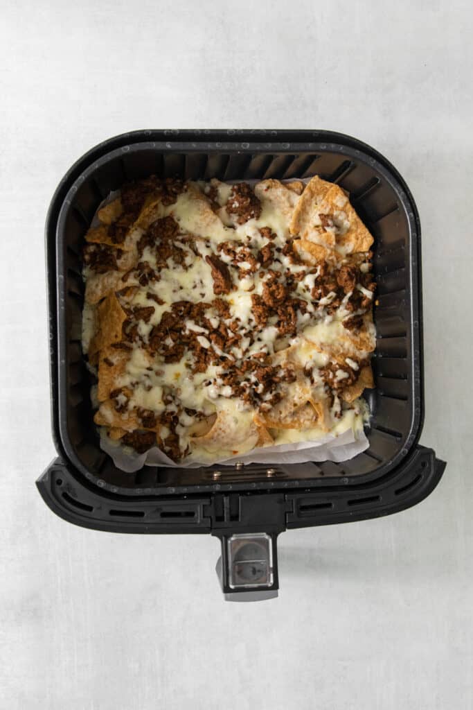 An air fryer filled with cheesy nachos.