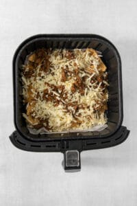 An air fryer filled with meat and cheese.