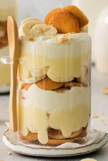 Banana trifle in a glass with a wooden spoon.