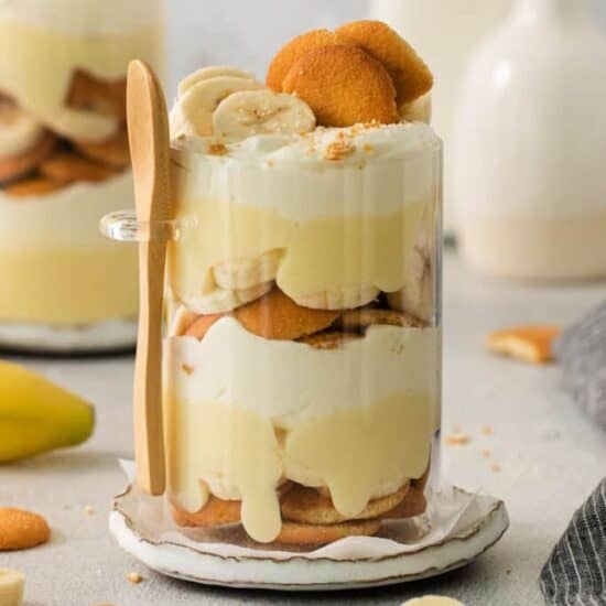 Banana trifle in a glass with a wooden spoon.