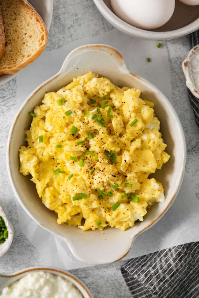 Scrambled eggs with chives and bread on a table.
